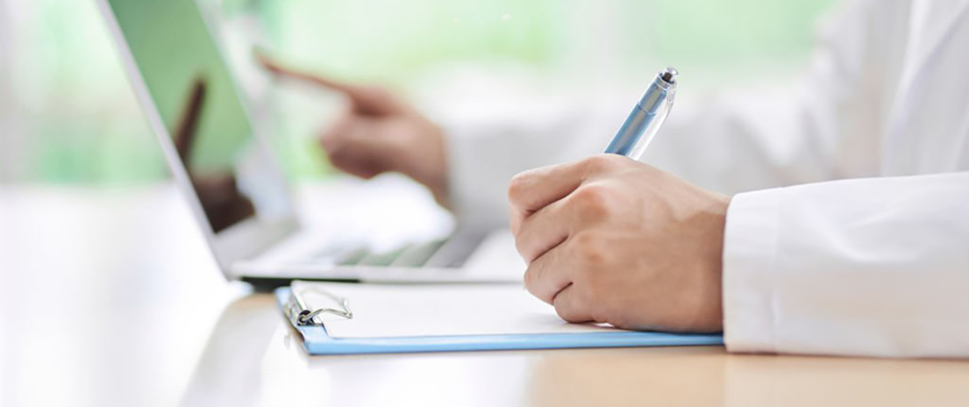A male doctor who looks up on a computer and takes notes